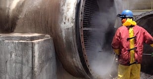 Operador fazendo hidrojateamento de alta pressão em equipamento industrial